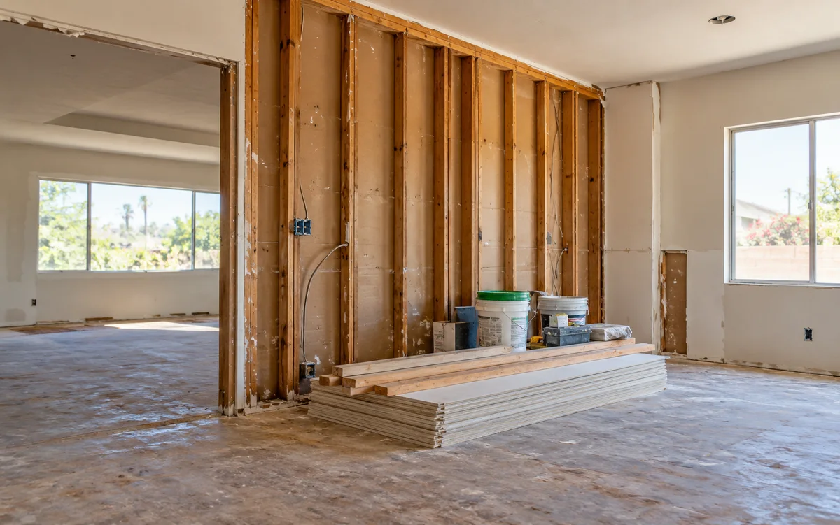 Illustrative unfinished home repairs with exposed wall studs and renovation supplies