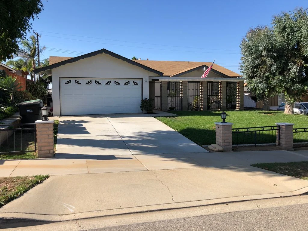 Front exterior of the Avenida Del Vista home in Corona, with an attached garage, driveway and lawn.