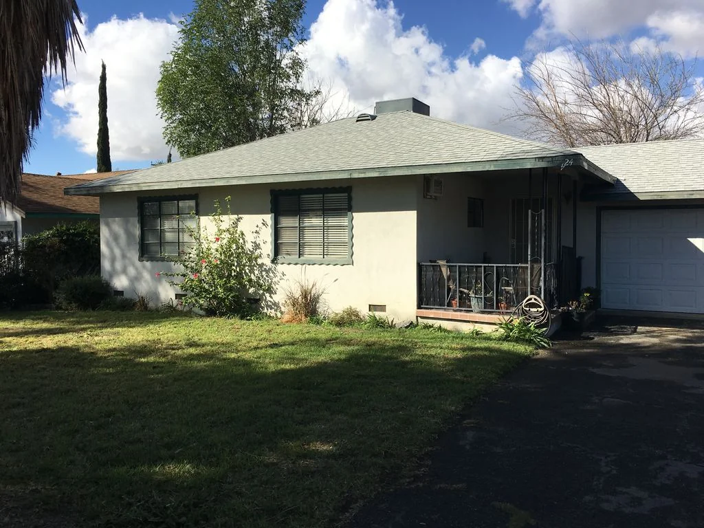 Front exterior of the house at 9424 Locust Avenue in Fontana, with a lawn, covered porch and attached garage