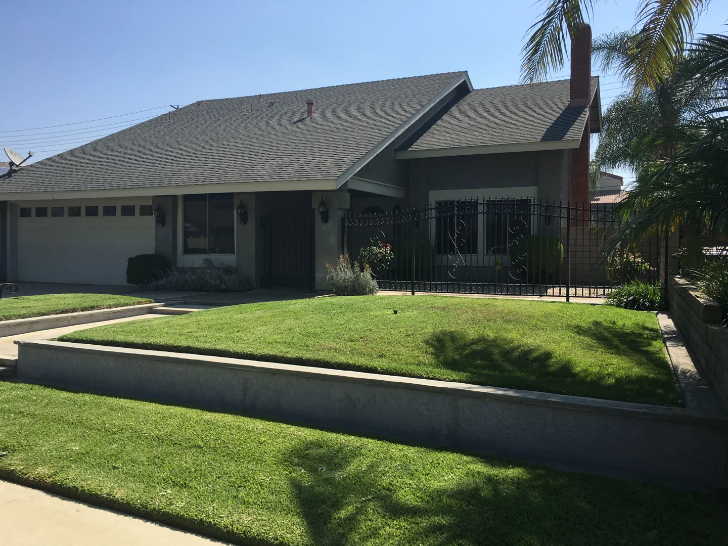 Front exterior of 2703 South Parkside Drive in Ontario, California, with a lawn, covered entry and palm trees.